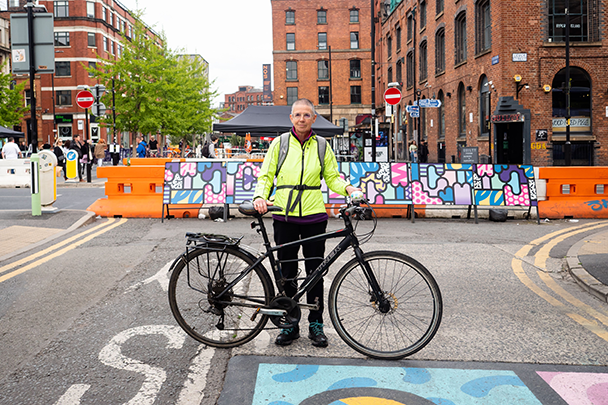 来自曼彻斯特的64岁的莉齐·金特穿着一件荧光黄色的夹克，骑着自行车站在路上。莉齐说:“老年人都过着精彩有趣的生活，他们有自己的故事，承认这一点很重要。”